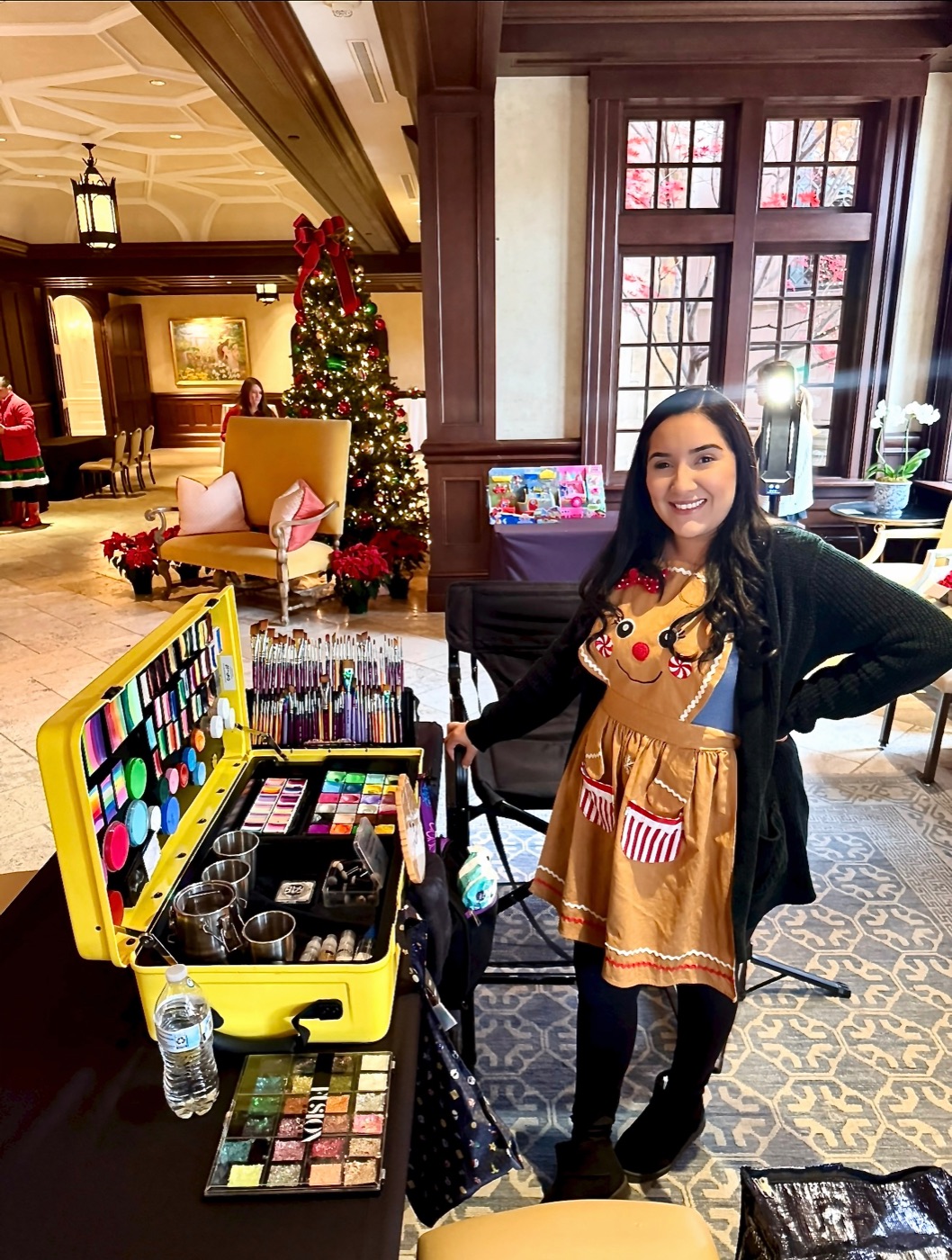 A CandyProArt artist with a colorful face painting station at a holiday event