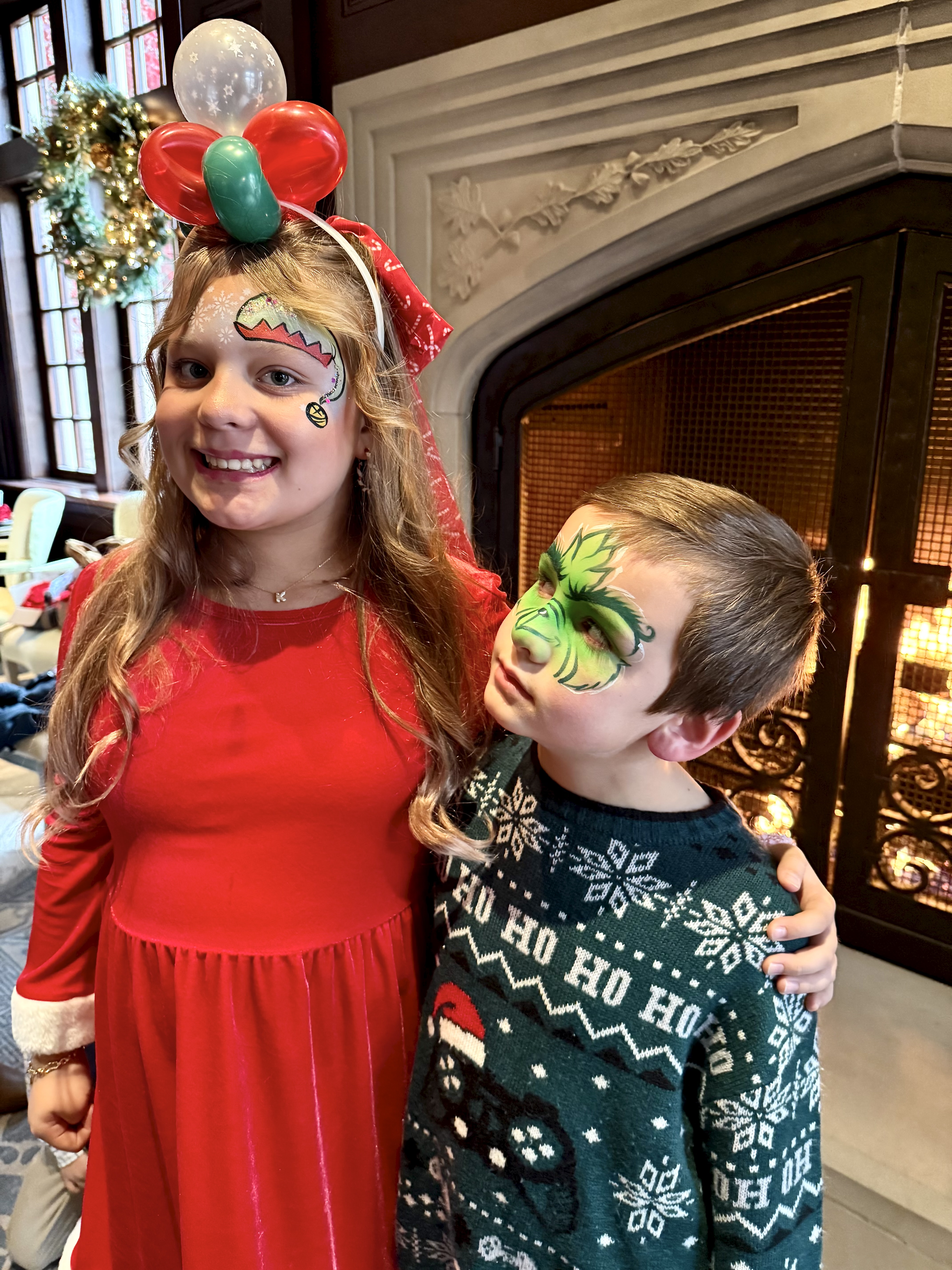 Two children with holiday face painting and a balloon headband