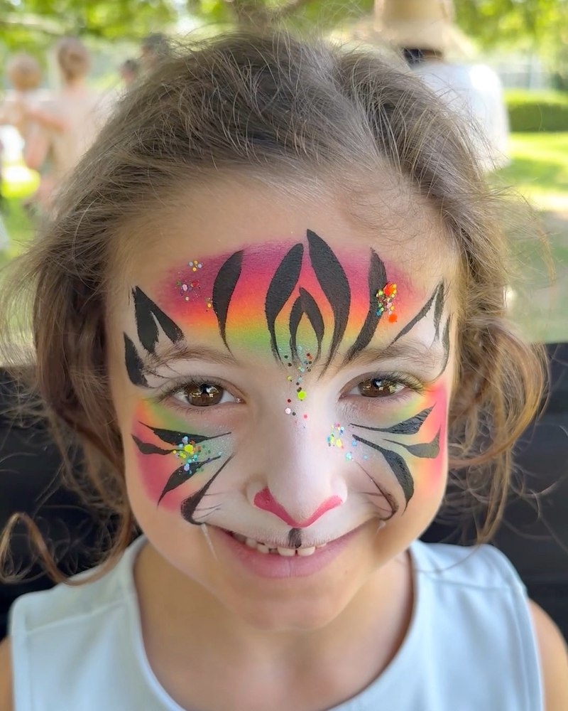 Rainbow tiger face painting by CandyProArt, with colorful stripes and delicate details